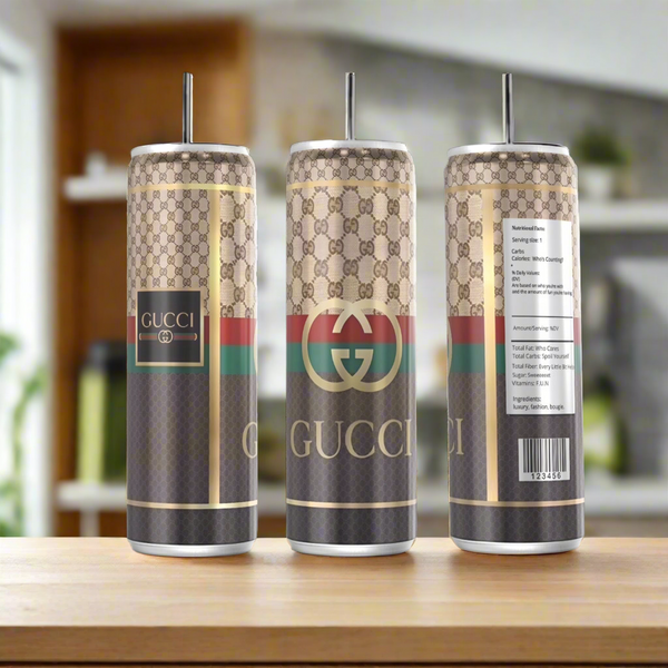 Three Gucci Silver Stainless Steel Inspired 20oz Tumblers by Kreative Kreationz, each with a metal straw and eco-friendly reusable design, rest on wood; one features a faux nutrition label against a blurred kitchen backdrop.