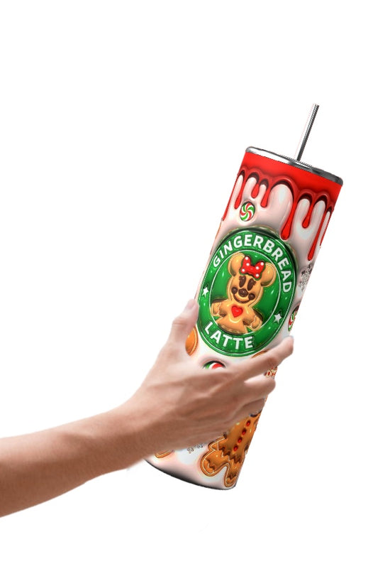A hand holds a tall Gingerbread 20oz Tumbler by Kreative Kreationz, featuring a gingerbread latte design. The tumbler displays gingerbread men, a candy cane, and dripping icing details on the lid. A metal straw complements its durable construction, ensuring both style and functionality.