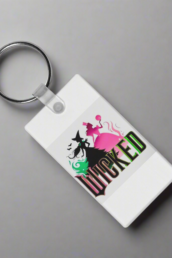 The Kreative Kreationz Wicked Keychain is a sturdy white accessory with vibrant sublimation art of two witches—one green, one pink—and 