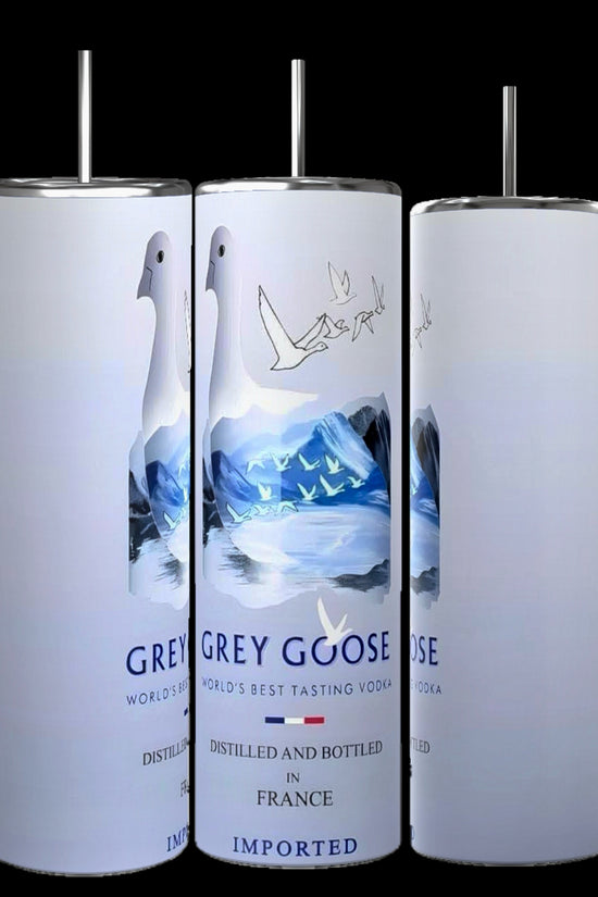 Three cylindrical bottles of Grey Goose vodka are displayed against a black background. The bottles feature a white label with an illustration of geese flying over blue and white landscapes and are marked with text indicating the vodka is distilled in France. Experience this sleek design now featured on the new, durable Grey Goose 20oz Tumbler by Kreative Kreationz.