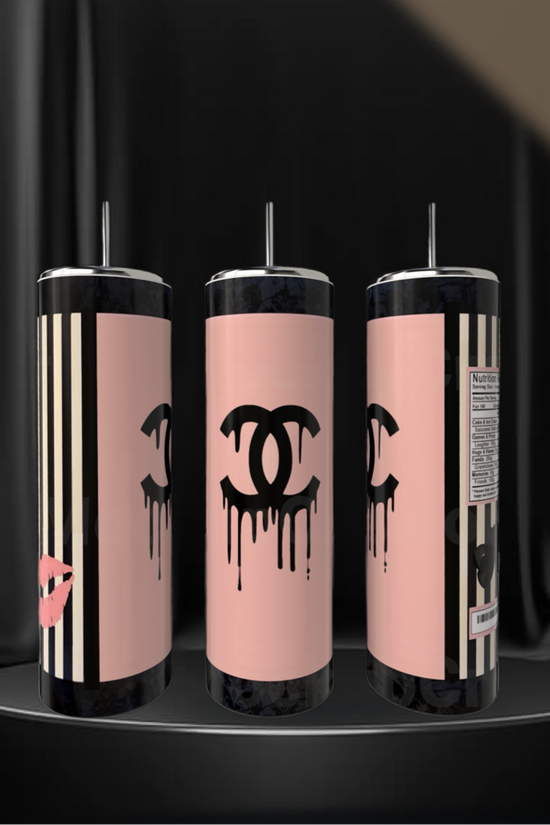 Three Chanel 20oz Skinny Tumblers by Kreative Kreationz, featuring pink and black designs with a dripping Chanel logo, lipstick print, stripes, and a nutrition label, rest stylishly on a black pedestal—eco-friendly drinkware for any occasion.