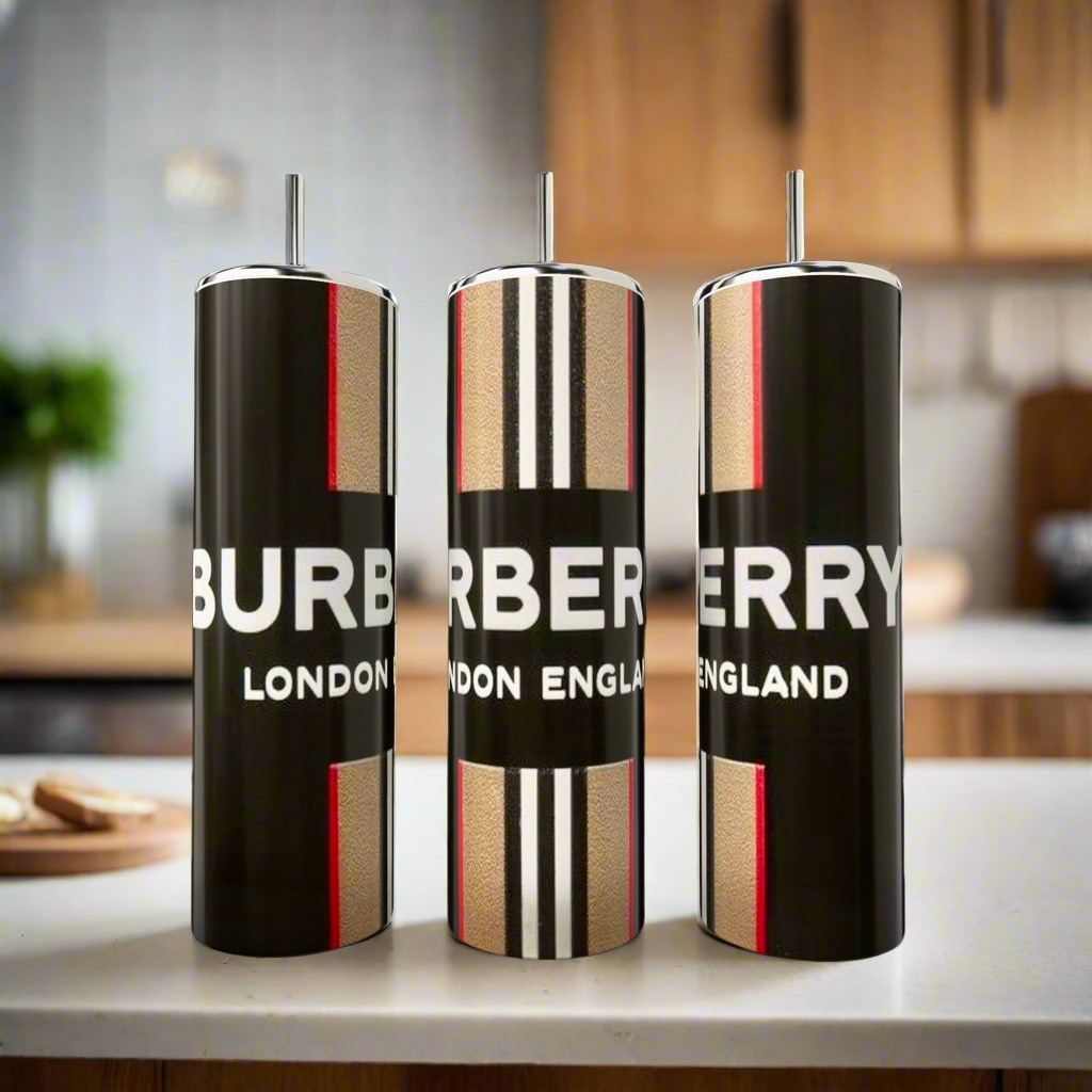 Three Burberry 20oz Skinny Tumblers by Kreative Kreationz, featuring bold black, white, and red designs on stainless steel luxury drinkware with straws, stand on a kitchen counter against a blurred background.