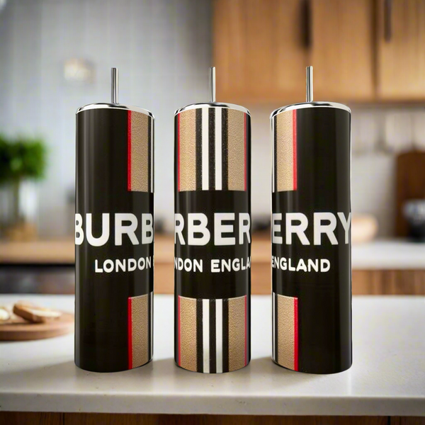 Three Burberry 20oz Skinny Tumblers by Kreative Kreationz, featuring bold black, white, and red designs on stainless steel luxury drinkware with straws, stand on a kitchen counter against a blurred background.