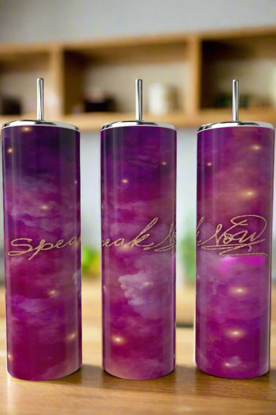 Three tall Kreative Kreationz Speak Now 20oz tumblers with straws feature a purple and pink gradient stainless steel design and gold script. Arranged on a wooden table, they stand out against blurred shelves and plants in the background.