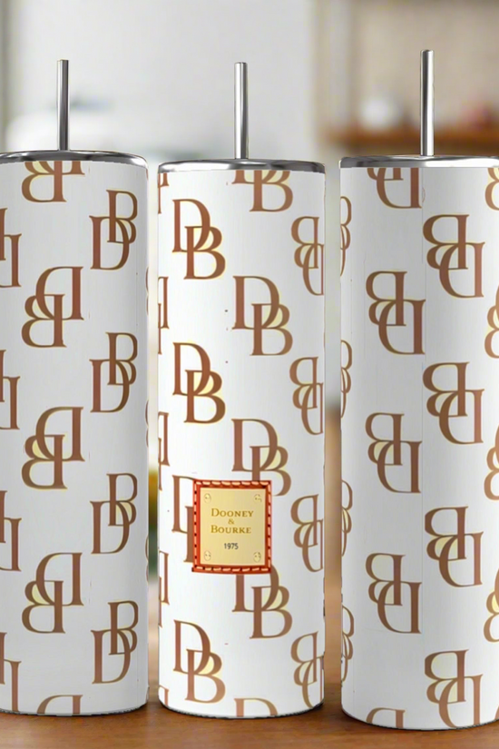 Three D&B -White | Brown 20oz Tumblers by Kreative Kreationz with brown monogram patterns and silver straws are shown. The center tumbler boasts a red and gold 