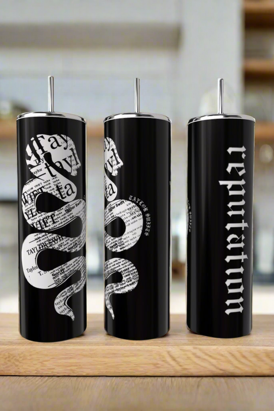 Three black 20oz Look What You Made Me Do skinny tumblers by Kreative Kreationz with silver lids and straws sit on a counter—two with white snake and newspaper designs, the third featuring 
