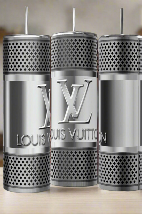 Three LV Silver Stainless Steel 20oz Tumblers by Kreative Kreationz stand upright on a wooden surface, showcasing luxury-inspired design, engraved branding and logo, perforations, and metal straws against a blurred kitchen background.