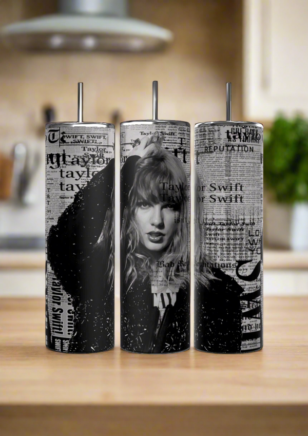 Three Kreative Kreationz Taylor Swift Reputation Newspaper 20oz Tumblers, each with black-and-white images and newspaper-style text plus spill-proof lids and reusable straws, are displayed on a wooden kitchen counter with a softly blurred background.