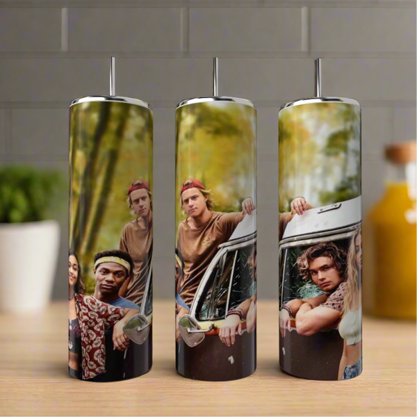 Three Pogues OBX 20oz Tumblers by Kreative Kreationz, each with a photo of four young adults by a vintage van in the woods, come with straws. They're shown on a kitchen counter with bottles and a plant in the background.