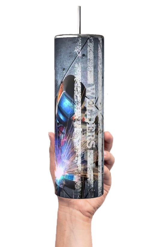 A hand holds a Welder 20oz Tumbler from Kreative Kreationz, featuring a metallic design and an image of a welder against a distressed American flag. This tall, cylindrical tumbler is part of the Welders Collection and includes a metal straw protruding from the lid.