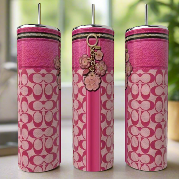Three Coach 20oz Tumblers by Kreative Kreationz, featuring pink patterned stainless steel and metallic straws, are displayed with floral keychain accents against a blurred green and beige background.