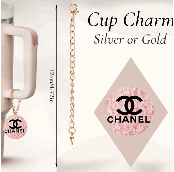 A gold cup charm from Kreative Kreationz, the Chanel Pink Charm Dangle, features a pink round pendant with the Chanel logo. Shown hanging from a mug with a lobster clasp silver chain. Text: “Cup Charm, Silver or Gold, 12cm/4.72in.”.
