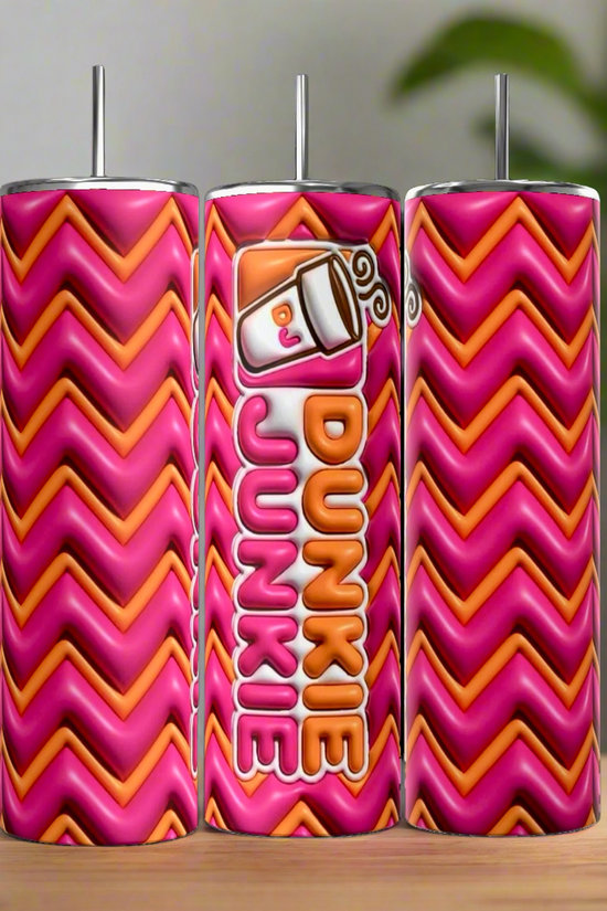 Three Kreative Kreationz Dunkin Junkie 20oz Tumblers, in pink and orange zigzag, stand on wood. The middle tumbler displays a coffee cup graphic with 