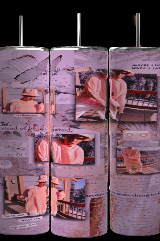 The Justin Bieber 20oz Tumbler by Kreative Kreationz showcases a vertical cylindrical design adorned with various photos and text fragments. The photos depict Justin Bieber wearing a hat and light clothing, captured in different poses. The durable tumbler features a background collage that includes images of butterflies, a watch, and cursive handwritten notes.