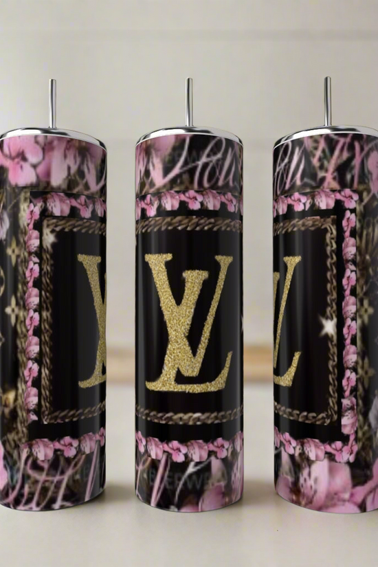 Three Kreative Kreationz LV Pink & Black 20oz Tumblers, featuring pink floral and black designs with a gold “LV” logo, exemplify luxury drinkware as they sit on a light countertop in a softly blurred kitchen setting.