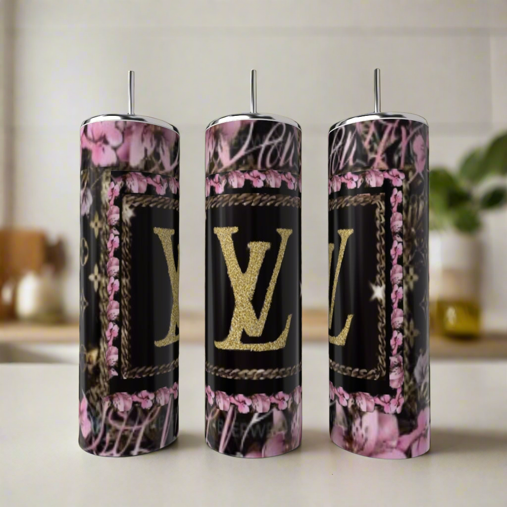 Three Kreative Kreationz LV Pink & Black 20oz Tumblers, featuring pink floral and black designs with a gold “LV” logo, exemplify luxury drinkware as they sit on a light countertop in a softly blurred kitchen setting.
