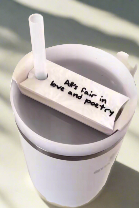 Stanley tumbler with showcasing white lid topper that says “alls fair in love and poetry” from taylor swifts album TTPD