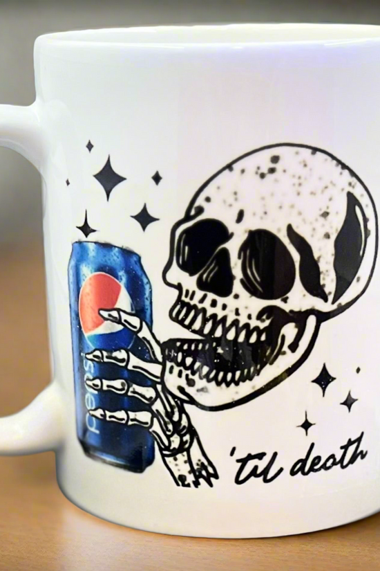 The Kreative Kreationz Pepsi to death Skull Ceramic Mug showcases a grinning skeleton holding a Pepsi can, surrounded by stars, with “‘til death” written below.