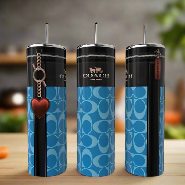 Three Coach Deep Blue Red Heart 20oz Skinny Tumblers by Kreative Kreationz, featuring the Coach logo, blue-and-black pattern, metal straws, and a red heart keychain, are displayed on wood with a blurred background.