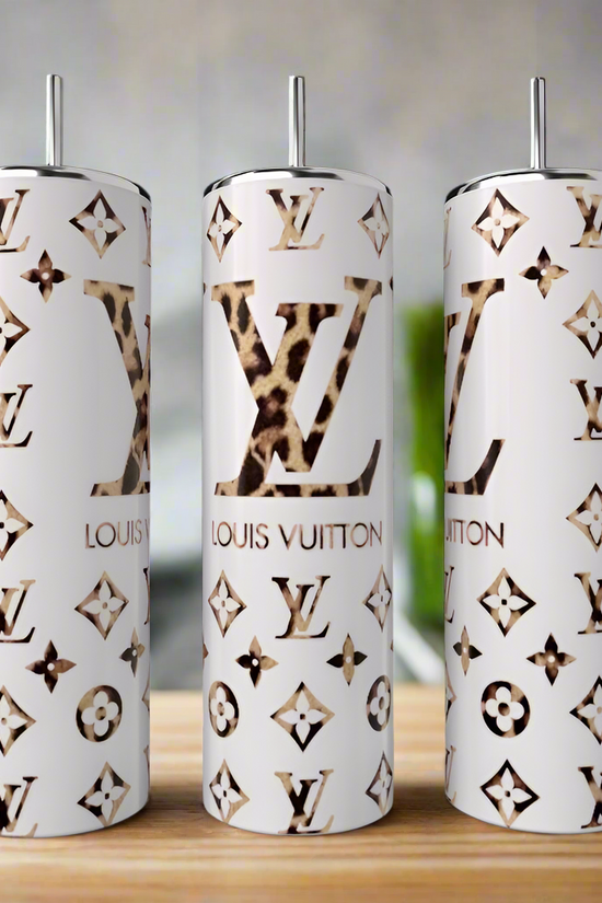 Three Kreative Kreationz LV Designed 20oz Tumblers with metal straws feature gold and leopard print accents, Louis Vuitton-inspired monogram, and high-quality stainless steel, shown on a wooden surface in a modern kitchen.