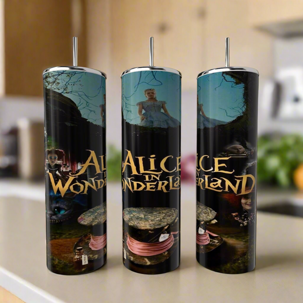 Three Kreative Kreationz Alice in Wonderland 20oz Tumblers, each with metal straw and colorful designs featuring the Cheshire Cat, scenes, and film title, stand on a kitchen counter with a blurred background.