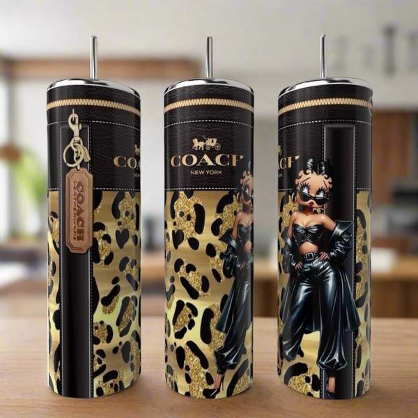Three Kreative Kreationz 20oz tumblers, including the Betty Boop Gold, are shown from different angles on a wooden surface with gold and black leopard print and unique designs.