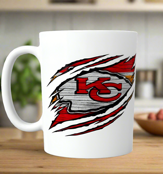 The Chiefs Ceramic Mug | 11oz by Kreative Kreationz features a sublimated design that appears to tear through the white ceramic, showcasing the bold red, yellow, and white Kansas City Chiefs logo—perfect for any cozy kitchen.