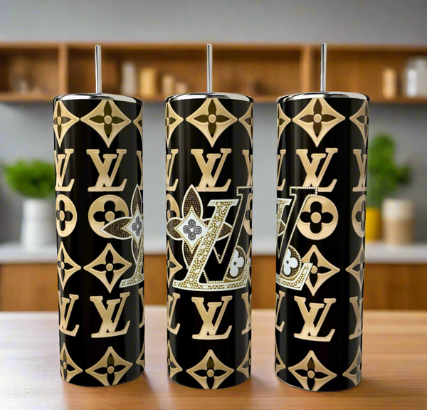 Three black Kreative Kreationz LV Glitz 20oz Skinny Tumblers with metallic lids and straws sit on a wooden counter, each adorned with a gold monogram design. These eco-friendly tumblers add style to any kitchen.