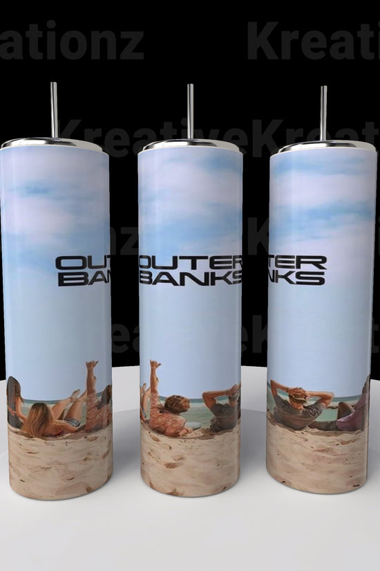 Three Outer Banks OBX 20oz Tumblers by Kreative Kreationz, tall and cylindrical, rest on a round white platform. Displaying a beach scene with 