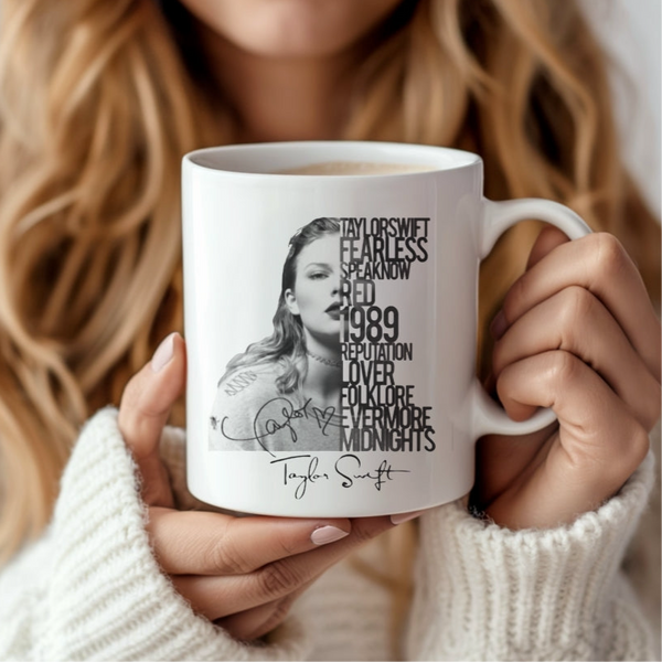 A woman in a white sweater holds the Rep Ceramic Mug by Kreative Kreationz, featuring a black-and-white Taylor Swift image, her signature, and bold album titles—a perfect gift for any Swiftie fan.