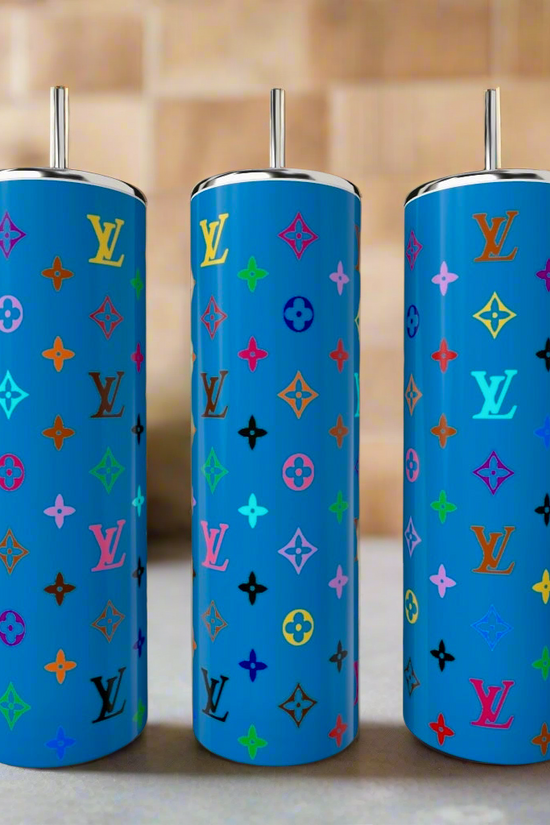 Three LV Blues 20oz Tumblers by Kreative Kreationz with colorful repeating Louis Vuitton monograms and metallic straws stand together against a blurred kitchen backdrop. Each luxury stainless steel piece is tall and blue.