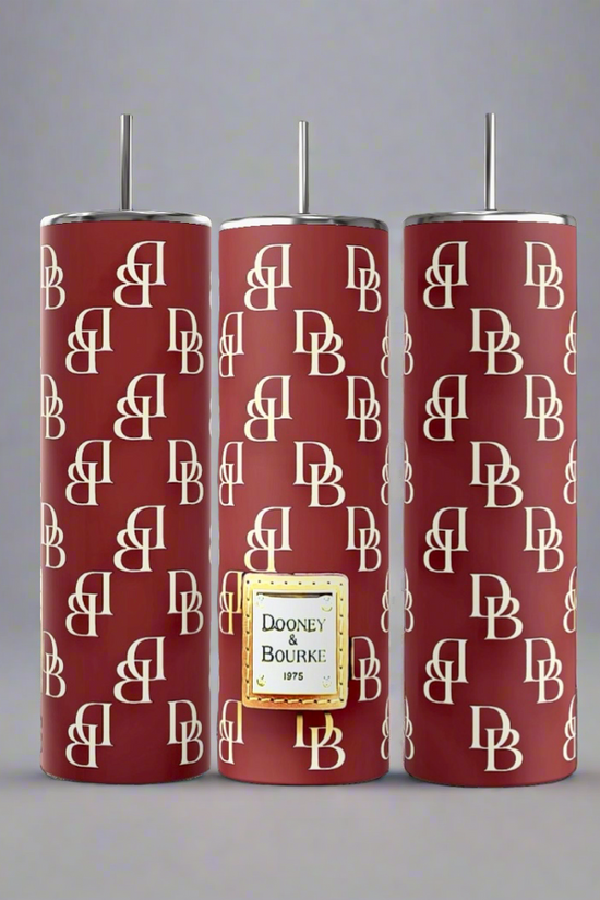 Three dark blue cylindrical tumblers, inspired by the luxury GUCCI Diana design and crafted by Kreative Kreationz, each featuring a textured pattern. These elegant tumblers boast prominent gold and red buckle designs, include a reusable straw, and flaunt a sleek, minimalistic aesthetic against a dark blue background. Each tumbler has an impressive 20 oz capacity.
