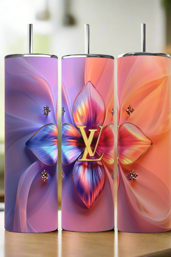 Three tall, cylindrical LV Puffy 20oz Tumblers by Kreative Kreationz come complete with metal straws. The first tumbler showcases a gradient background transitioning from blue to violet, adorned with a large, colorful floral centerpiece. The middle and right tumblers feature similar floral designs, each boasting unique color gradients and durable construction for maximum longevity.
