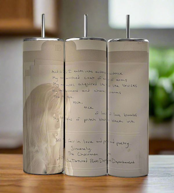 The Manuscript TTPD 20oz Tumblers by Kreative Kreationz feature handwritten poetry and a faded sketch on stainless steel, set side by side on wood with a blurred kitchen backdrop.