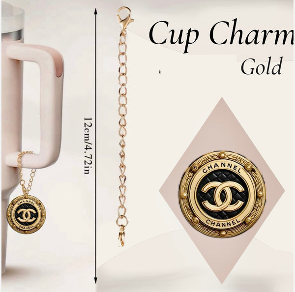 The Chanel Charm Dangle | Cup Accessory by Kreative Kreationz features a 12cm gold chain with a black and gold “CHANNEL” medallion and double C logo, shown attached to a mug. Add custom charms or a personalized pendant for extra flair.