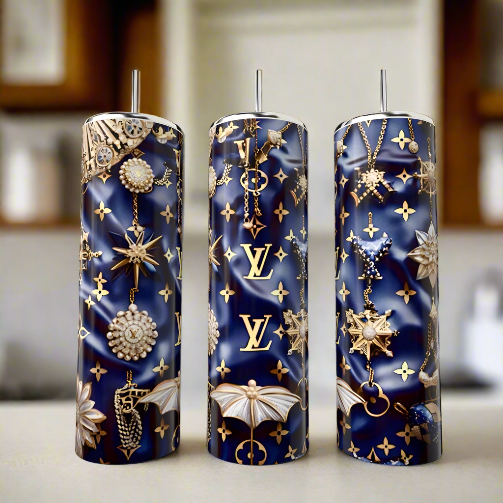 The Kreative Kreationz LV Blue & Gold 20oz Tumbler is a tall, navy eco-friendly luxury drinkware with silver straw, gold LV logo, and jewel-inspired star, moth & chain designs—an elegant choice for any kitchen counter.