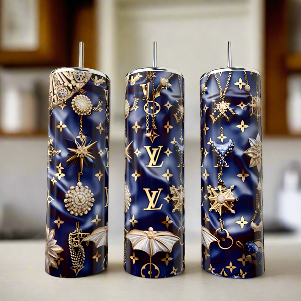 The Kreative Kreationz LV Blue & Gold 20oz Tumbler is a tall, navy eco-friendly luxury drinkware with silver straw, gold LV logo, and jewel-inspired star, moth & chain designs—an elegant choice for any kitchen counter.