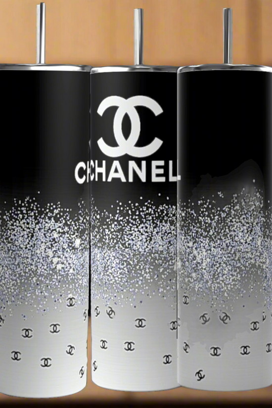The Chanel | Black and Glitter 20oz Skinny Tumbler by Kreative Kreationz features a black-to-white gradient, sparkling glitter, and Chanel logos with silver straws—perfectly displayed in a stylish kitchen.
