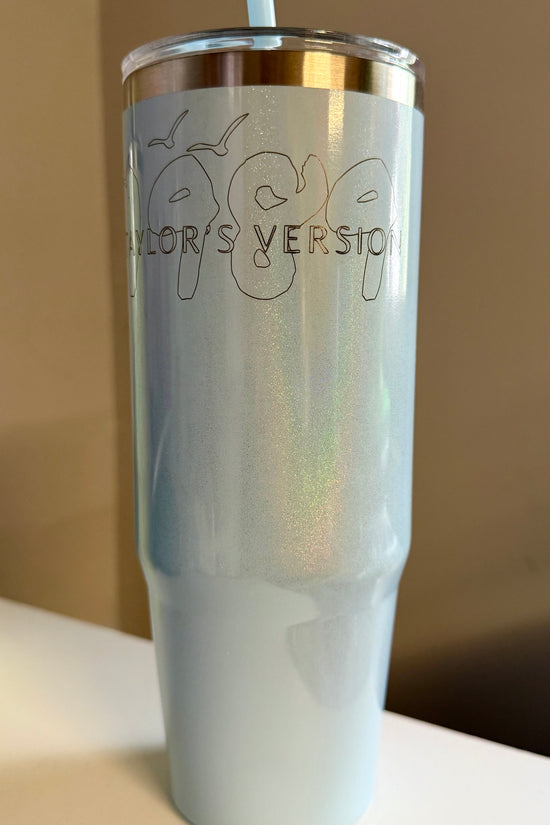 The Kreative Kreationz 1989 Taylor’s Version Shimmer Laser Engraved 30oz stainless steel tumbler is iridescent light blue with a metal rim, straw, and “1989 TAYLOR'S VERSION” outlined on the front.