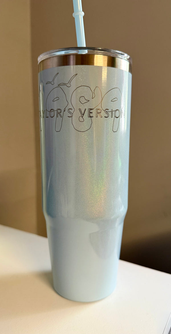 The Kreative Kreationz 1989 Taylor’s Version Shimmer Laser Engraved 30oz stainless steel tumbler is iridescent light blue with a metal rim, straw, and “1989 TAYLOR'S VERSION” outlined on the front.