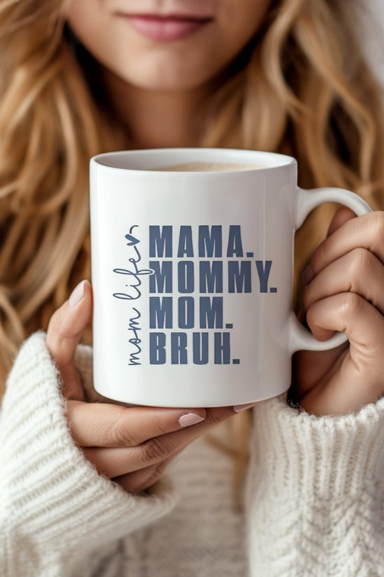 A woman with long blonde hair in a cozy white sweater holds the Kreative Kreationz Mom Bruh Mug, a dishwasher safe ceramic mug featuring 