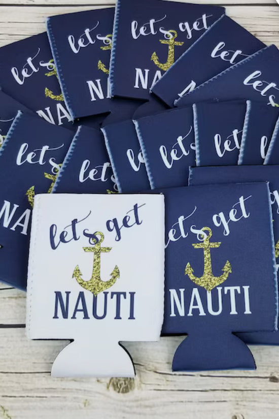 A set of Nautical Beach Theme 6-Pack Customizable Koozies from Kreative Kreationz is scattered on a wooden surface. These navy blue and white coolers are adorned with a gold anchor design and the phrase 