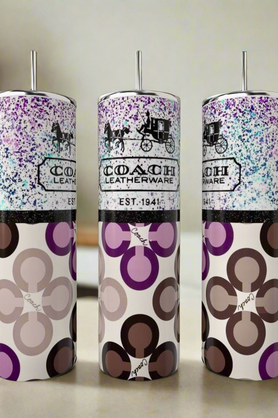 On the kitchen counter are three stainless steel tumblers with metal straws and modern geometric Coach Leatherware patterns, including the stylish Coach Purple Designed 20oz Tumbler by Kreative Kreationz in blue, brown, and purple hues.