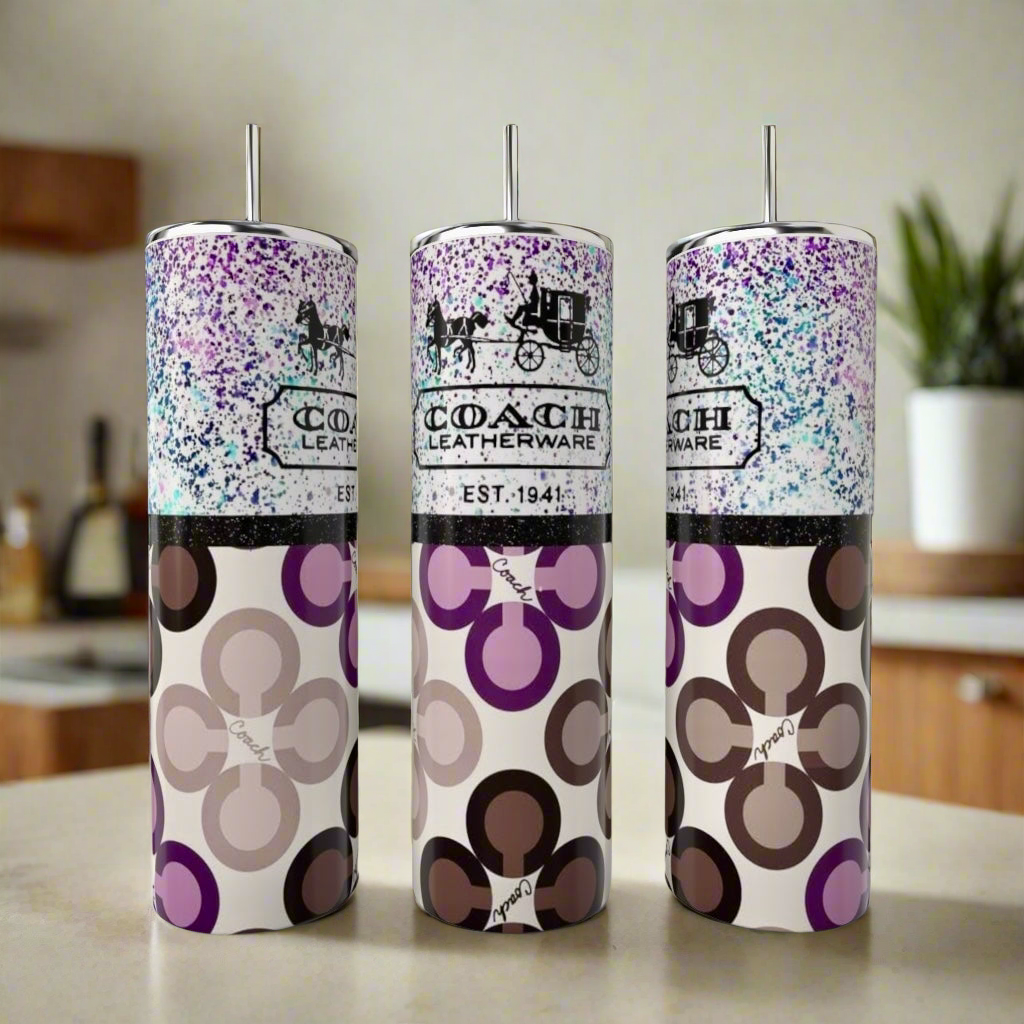 On the kitchen counter are three stainless steel tumblers with metal straws and modern geometric Coach Leatherware patterns, including the stylish Coach Purple Designed 20oz Tumbler by Kreative Kreationz in blue, brown, and purple hues.