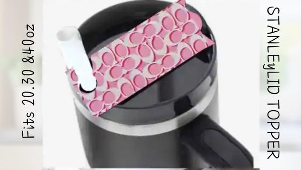 The Pink Stanley Lid Plate/Topper by Kreative Kreationz features a pink and white pattern inspired by Louis Vuitton, designed for black Stanley tumblers (20, 30 & 40oz) with handle and straw. "STANLEY LID TOPPER" is displayed on the side.