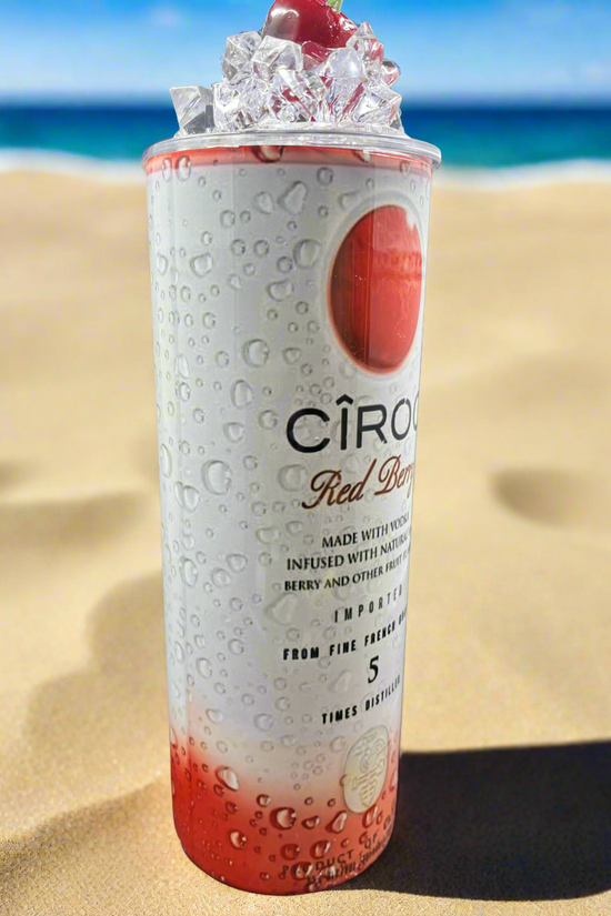 Two cans of Kreative Kreationz Ciroc 20oz Tumbler with 3D Lid Topper are shown on a wooden surface, reminiscent of travel tumblers. The left can is Red Berry flavor, topped with ice and a cherry. The right can is Vodka Snap Frost flavor, topped with ice and a lemon slice. Both cans feature product information and branding.