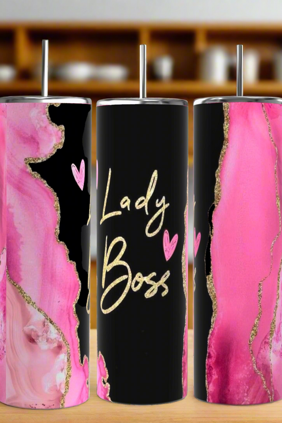 The Kreative Kreationz Boss Lady 20oz Tumbler set includes three tall tumblers with spill-proof lids and reusable straws, featuring pink, black, and gold abstract designs. The center tumbler displays 