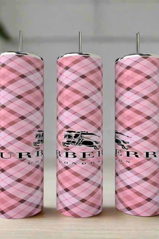 Three Burberry 20oz Skinny Tumblers by Kreative Kreationz, featuring pink plaid and the London logo, stand side by side on a light surface with their luxurious design highlighted against a softly blurred background.