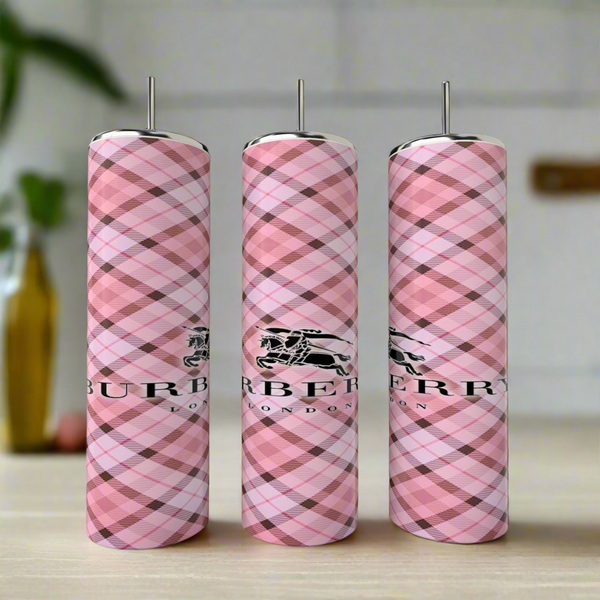 Three Burberry 20oz Skinny Tumblers by Kreative Kreationz, featuring pink plaid and the London logo, stand side by side on a light surface with their luxurious design highlighted against a softly blurred background.