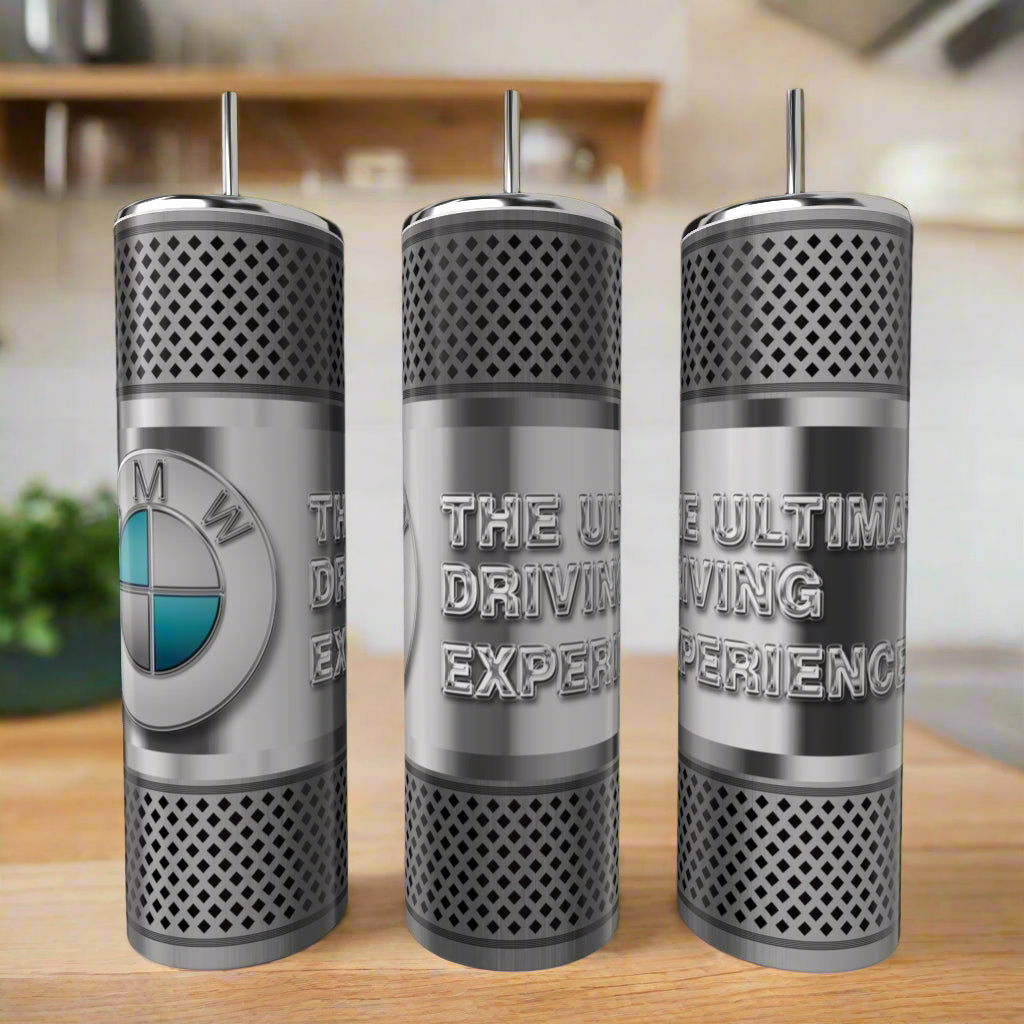 Three Kreative Kreationz Car Enthusiast Silver Stainless Steel 20oz Tumblers are shown; one features a BMW logo, and the others read "THE ULTIMATE DRIVING EXPERIENCE." A blurred kitchen is visible in the background.